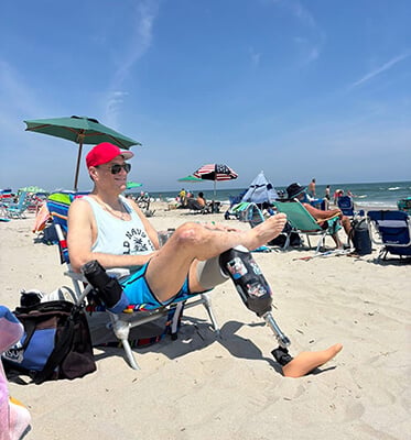 Photo of Kevin sitting in a chair at the beach with his prosthetic leg